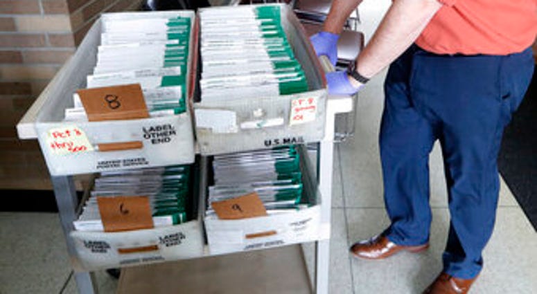 FILE - In this May 5, 2020, file photo, absentee ballots to be counted are moved at City Hall in Garden City, Mich. (AP Photo/Paul Sancya, File) FILE - In this May 5, 2020, file photo, absentee ballots to be counted are moved at City Hall in Garden City, Mich. (AP Photo/Paul Sancya, File)