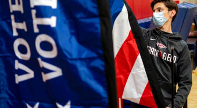 Thomas Hedrich sets up voting flags at a polling location in Gwinnett County, Ga., outside of Atlanta on Monday, Jan. 4, 2021, in advance of the Senate runoff election. (AP Photo/Ben Gray) Thomas Hedrich sets up voting flags at a polling location in Gwinnett County, Ga., outside of Atlanta on Monday, Jan. 4, 2021, in advance of the Senate runoff election. (AP Photo/Ben Gray)