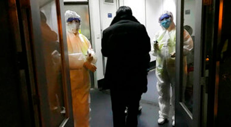 FILE - In this Wednesday, Jan. 22, 2020 file photo, Health Officials in hazmat suits wait at the gate to check body temperatures of passengers arriving from the city of Wuhan, at the airport in Beijing, China. (AP Photo Emily Wang, File) FILE - In this Wednesday, Jan. 22, 2020 file photo, Health Officials in hazmat suits wait at the gate to check body temperatures of passengers arriving from the city of Wuhan, at the airport in Beijing, China. (AP Photo Emily Wang, File)