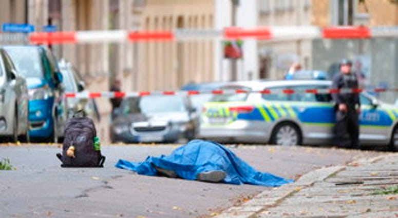 A body lies on a road in Halle, Germany after a shooting incident. A gunman fired several shots on Wednesday in German city of Halle and at least two got killed, according to local media FOCUS online. (Sebastian Willnow/dpa via AP)