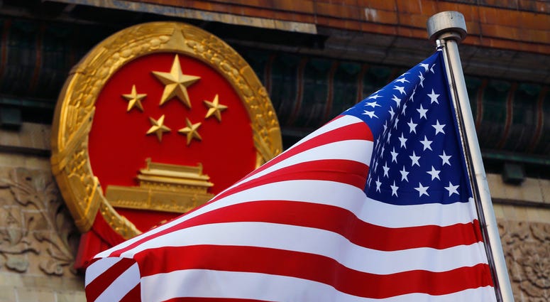 FILE - In this Nov. 9, 2017, file photo, an American flag is flown next to the Chinese national emblem during a welcome ceremony for visiting U.S. President Donald Trump outside the Great Hall of the People in Beijing. The State Department said an email n