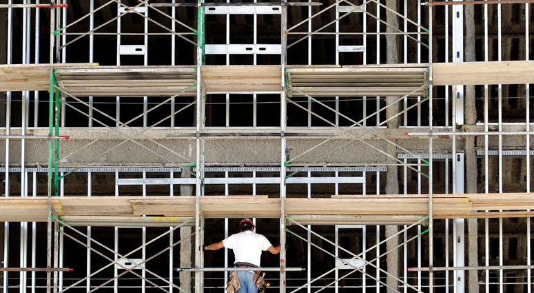 FILE- In this Friday, Oct. 6, 2017, file photo, a worker helps build an apartment and retail complex in Nashville, Tenn. The National Association for Business Economics says in its latest quarterly outlook that its panel of 45 economists expects the econo