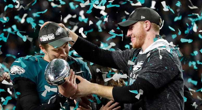 In this Feb. 4, 2018 photo, Philadelphia Eagles quarterback Carson Wentz, right, hands the Vincent Lombardi trophy to Nick Foles after winning the Super Bowl against the New England Patriots in Minneapolis. (AP Photo/Frank Franklin II)
