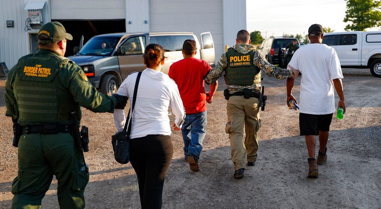 Government agents take suspects into custody during an immigration sting at Corso's Flower and Garden Center, Tuesday, June 5, 2018, in Castalia, Ohio. The operation is one of the largest against employers in recent years on allegations of violating immig
