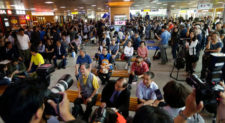 People watch a TV screen showing U.S. President Donald Trump meet with North Korean leader Kim Jong Un during a news program at the Seoul Railway Station in Seoul, South Korea, Tuesday, June 12, 2018. (AP Photo/Ahn Young-joon)