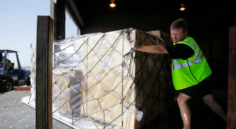 FILE- In this July 16, 2010, file photo, Mark Wilson pushes air cargo cleared for shipment to Santiago, Chile, at the American Airline cargo processing warehouse at Dallas-Fort Worth International Airport in Grapevine, Texas. U.S. authorities are requirin