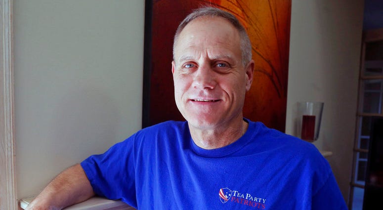 FILE - In this Feb. 16, 2018, photo, Andy Cilek poses with a Tea Party shirt at his home in Eden Prairie, Minn. Cilek was one of two voters who defied elections officials after he was asked to cover up a tea-party shirt and button. The Supreme Court has s