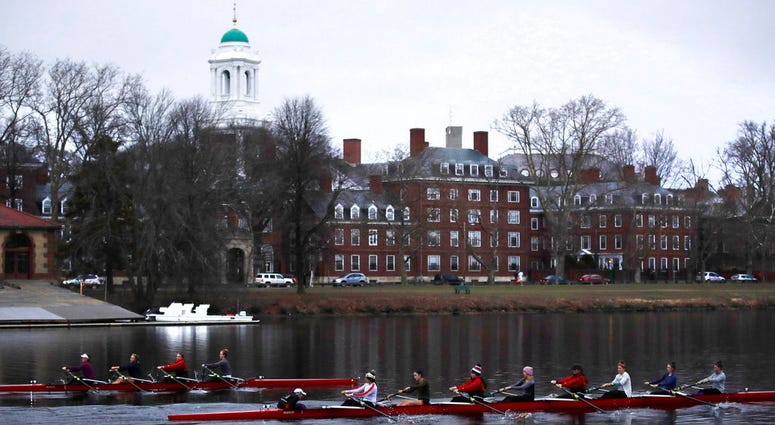 FILE-- In this March 7, 2017 file photograph, rowers pass the campus of Harvard University as they paddle down the Charles River in Cambridge, Mass. Harvard and the group Students for Fair Admissions will file dueling analyses of the Ivy League school's a