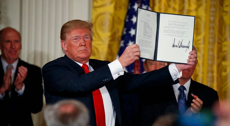 President Donald Trump shows off a "Space Policy Directive" after signing it during a meeting of the National Space Council in the East Room of the White House, Monday, June 18, 2018, in Washington. (AP Photo/Evan Vucci)