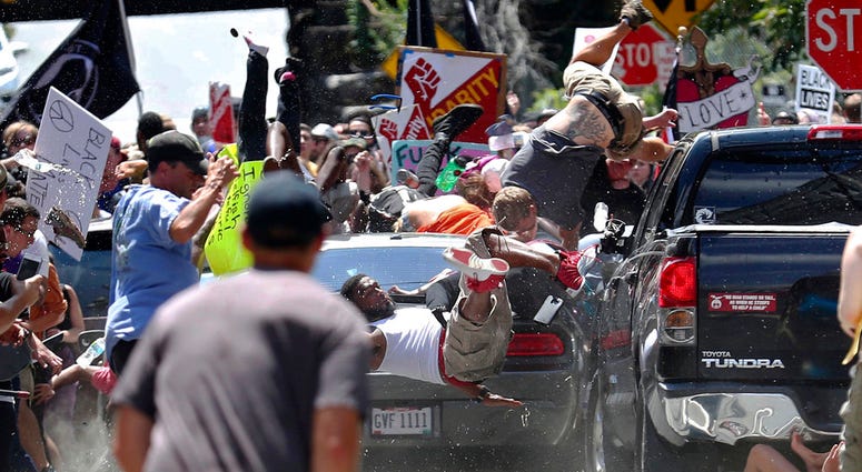 In this Aug. 12, 2017, file photo, people fly into the air as a vehicle is driven into a group of protesters demonstrating against a white nationalist rally in Charlottesville, Va. (Ryan M. Kelly/The Daily Progress via AP, File)