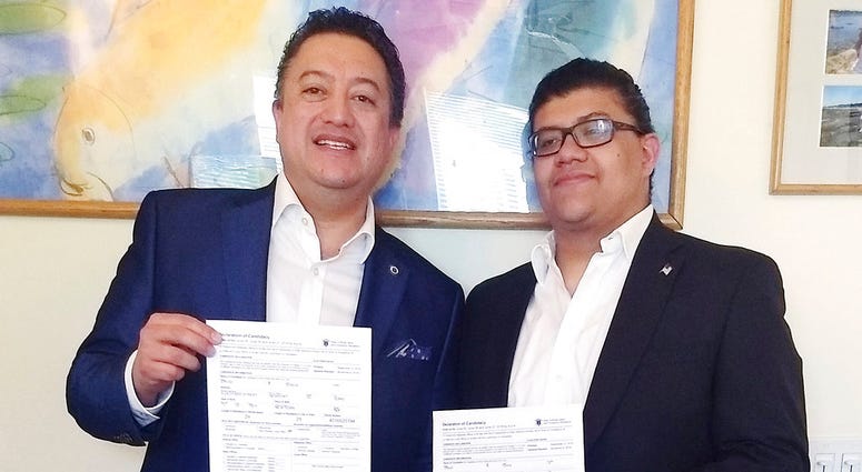 In this Tuesday, June 26, 2018 photo provided by David Quiroa, father David Quiroa, left, and son David Quiroa, Jr., right, hold their candidacy papers in Newport, R.I. The father will run as a Republican and the son will run as an independent in the Nove
