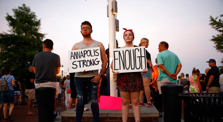 Tanner Piekarski, left, and Kylie Myles hold signs during a vigil in response to a shooting at The Capital Gazette newspaper office, Friday, June 29, 2018, in Annapolis, Md. (AP Photo/Patrick Semansky)