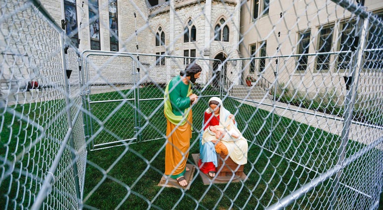 This Tuesday, July 3, 2018 photo shows statues of Mary, Joseph and the baby Jesus in a cage of fencing topped with barbed wired on the lawn of Monument Circle's Christ Church Cathedral in Indianapolis. The statues were erected to protest the Trump adminis