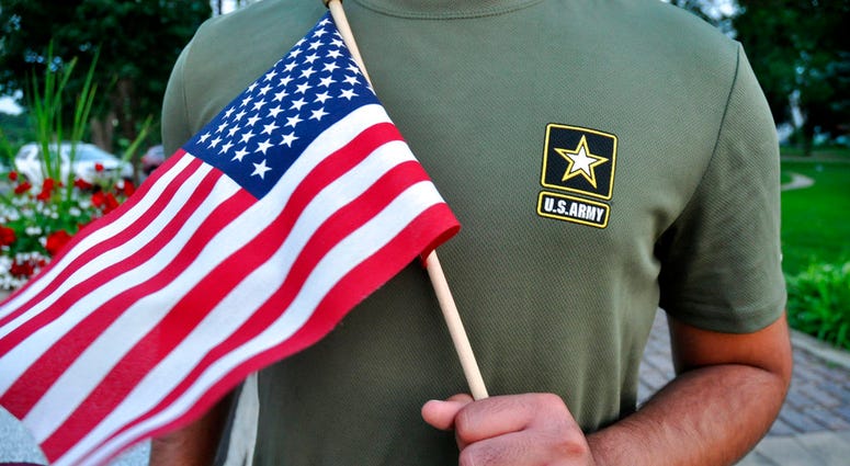 In this Tuesday, July 3, 2018, photo, a Pakistani recruit, 22, who was recently discharged from the U.S. Army, holds an American flag as he poses for a picture. The man asked his name and location to be undisclosed for safety reasons. The AP interviewed t