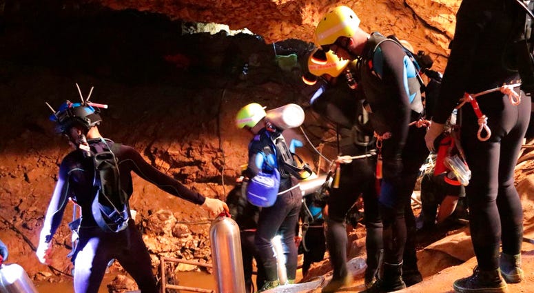 In this undated photo released by Royal Thai Navy on Saturday, July 7, 2018, Thai rescue team members walk inside a cave where 12 boys and their soccer coach have been trapped since June 23, in Mae Sai, Chiang Rai province, northern Thailand. The local go