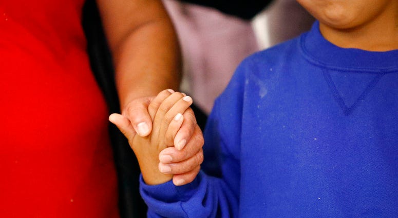 In this Friday, June 22, 2018, photo, a mother, left, and son, from Guatemala, hold hands following their reunion in Linthicum, Md., after being reunited following their separation at the U.S. border. (AP Photo/Patrick Semansky, File)