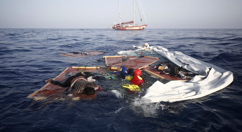 Rescue workers from the Proactiva Open Arms Spanish NGO retrieve the bodies of an adult and a child amid the drifting remains of a destroyed migrant boat off the Libyan coast, on Tuesday July 17, 2018. (Proactiva Open Arms via AP)