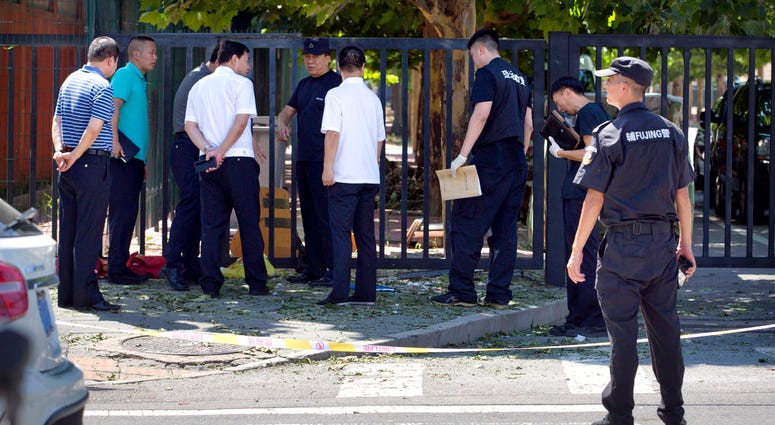Officials and security personnel stand near the site of reported blast just south of the U.S. Embassy in Beijing, Thursday, July 26, 2018. (AP Photo/Mark Schiefelbein)