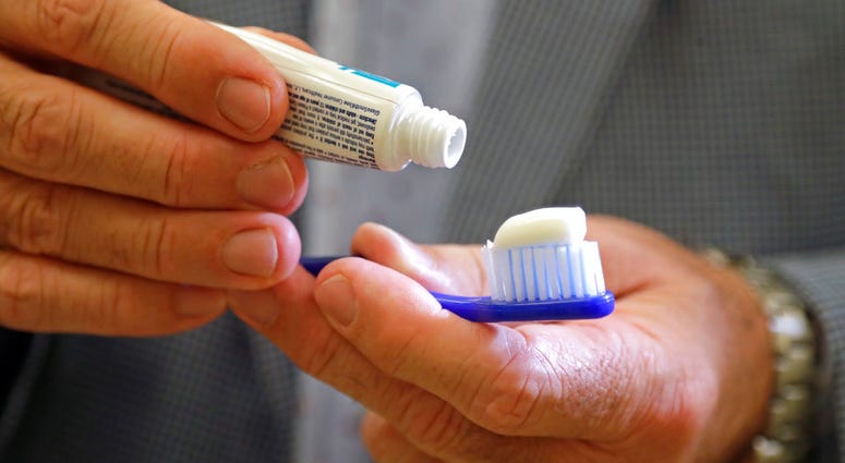 Philippe Hujoel, a dentist and University of Washington professor, holds a toothbrush and toothpaste in an office at the school in Seattle. (AP Photo/Elaine Thompson)