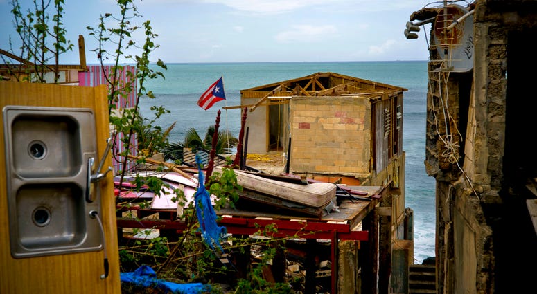 FILE - In this Oct. 5, 2017 file photo, a Puerto Rican national flag is mounted on debris of a damaged home in the aftermath of Hurricane Maria. (AP Photo/Ramon Espinosa) FILE - In this Oct. 5, 2017 file photo, a Puerto Rican national flag is mounted on debris of a damaged home in the aftermath of Hurricane Maria. (AP Photo/Ramon Espinosa)