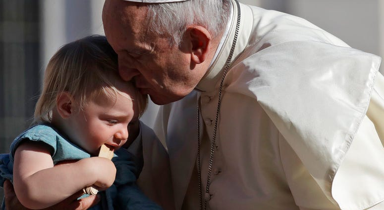 El papa Francisco besa a un niño al arribar a la plaza de San Pedro en el Vaticano para su audiencia general semanal, 5 de septiembre de 2018.