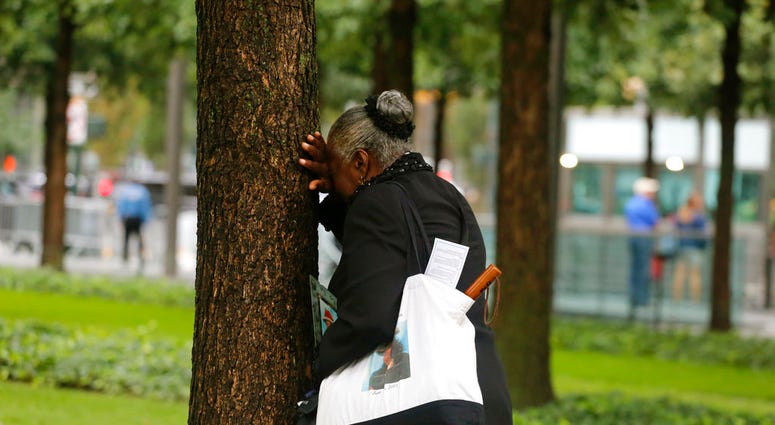 A woman weeps by herself as she leans against a tree during a ceremony marking the 17th anniversary of the terrorist attacks on the United States. Tuesday, Sept. 11, 2018, at the World Trade Center in New York