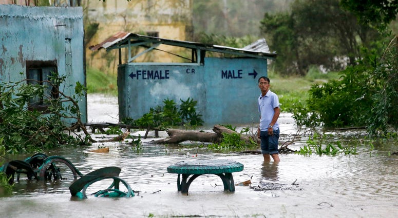 A resident wades along a flooded area as Typhoon Mangkhut barreled across Tuguegarao city in Cagayan province, northeastern Philippines on Saturday, Sept. 15, 2018