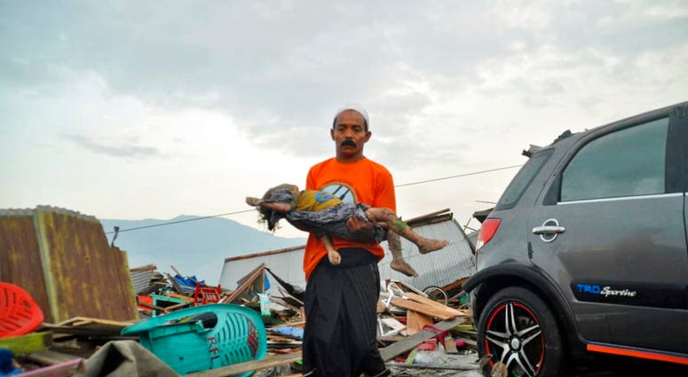 A man carries the body of a child who was killed in the tsunami in Palu, Central Sulawesi, Indonesia, Saturday, Sept. 29, 2018.