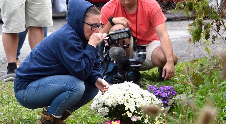 Woman knelling at make-shift memorial