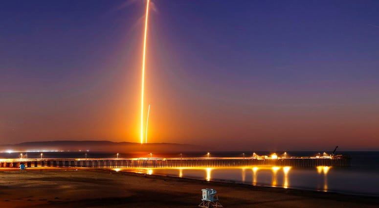 Two streaks in this long exposure photo show a SpaceX Falcon 9 rocket lifting off, left, from Vandenberg Air Force Base, as seen from Pismo Beach, Calif. Sunday, Oct. 7, 2018, and then its first stage returning, right, to Earth at a nearby landing pad