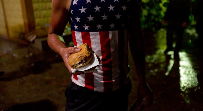 A Honduran migrant holds a sandwich at an improvised shelter in Chiquimula, Guatemala, Tuesday, Oct. 16, 2018. (AP Photo/Moises Castillo)