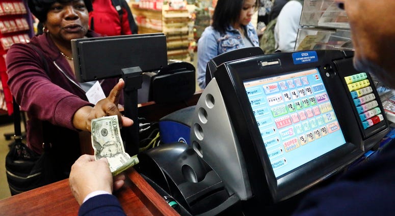 Annette Gray, left, from Valley Stream, N.Y., buys lottery tickets Friday Oct. 19, 2018, in New York. (AP Photo/Bebeto Matthews)