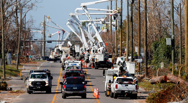 In this Thursday, Oct. 18, 2018 photo, utility crews set up new poles and utility wires in the aftermath of Hurricane Michael in Panama City, Fla