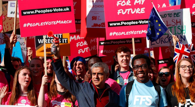 Mayor of London Sadiq Khan, front centre, holds a klaxon horn, as he joins protesters in the People's Vote March for the Future, in London, Saturday Oct. 20, 2018.
