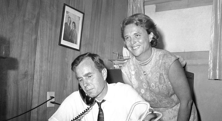 n this June 6, 1964, file photo George H.W. Bush, candidate for the Republican nomination for the U.S. Senate, gets returns by phone at his headquarters in Houston, as his wife Barbara, smiles at the news.