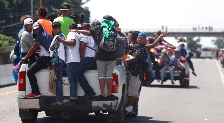 Central American migrants making their way to the U.S. in a large caravan cling to the trucks of drivers who offered them free rides, as they arrive to Tapachula, Mexico, Sunday, Oct. 21, 2018. (AP Photo/Moises Castillo)