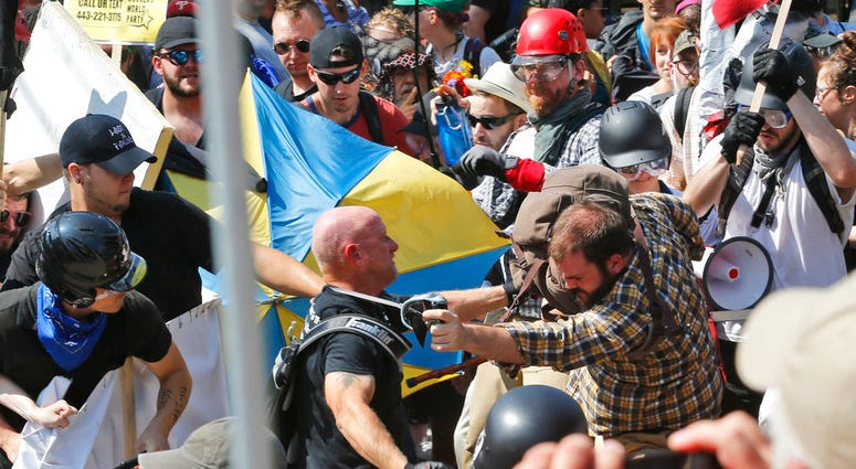 In this Aug. 12, 2017 file photo, white nationalist demonstrators clash with counter demonstrators at the entrance to Lee Park in Charlottesville, Va. (AP Photo/Steve Helber, File)