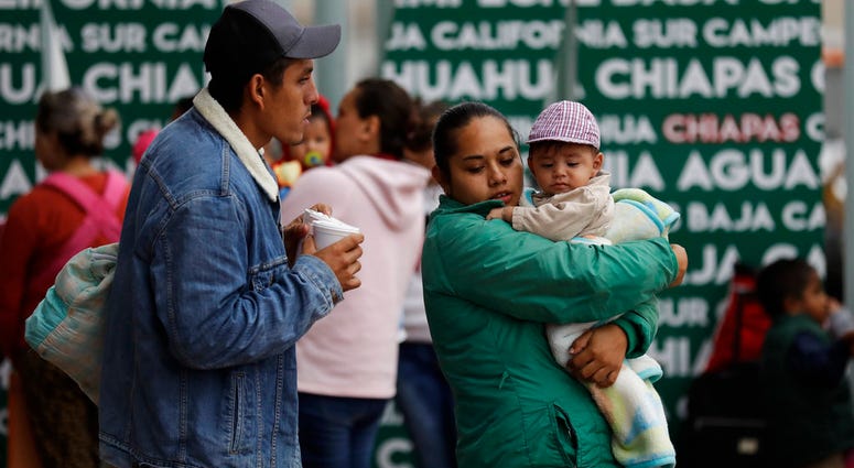 In this Oct. 23, 2018 image, people seeking asylum in the United States wait to receive a number at the border in Tijuana, Mexico. (AP Photo/Gregory Bull)