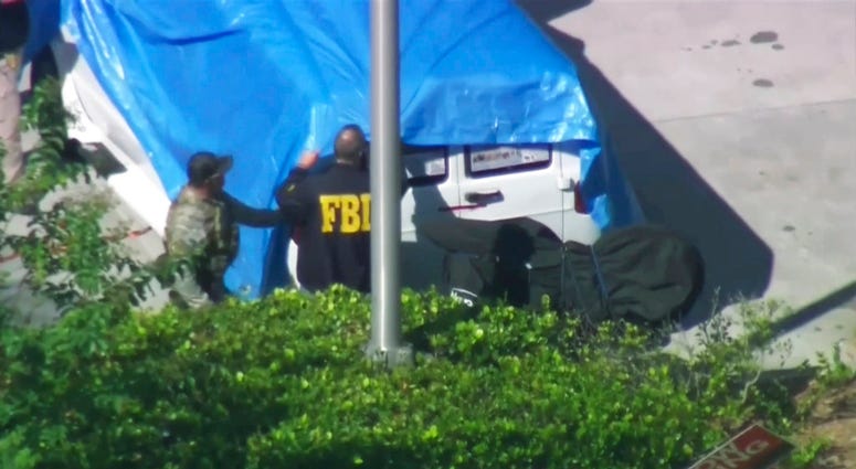 In this frame grab from video provided by WPLG-TV, FBI agents cover a van parked in Plantation, Fla., on Friday, Oct. 26, 2018. (WPLG-TV via AP)