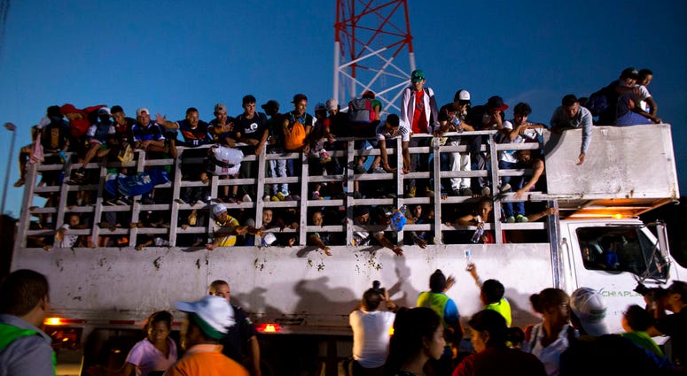 Men pass up water to Central Americans riding on the back of a truck while other migrants wait for rides, as a thousands-strong caravan of Central American makes its way toward the U.S. border,