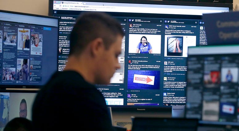 In this Oct. 17, 2018 file photo, a man works at his desk in front of monitors during a demonstration in the war room, where Facebook monitors election related content on the platform, in Menlo Park, Calif.
