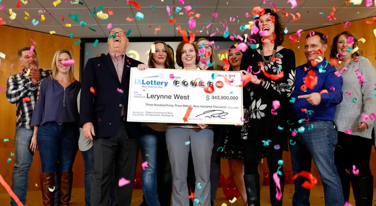Iowa Lottery CEO Terry Rich, left, presents a check to Lerynne West, of Redfield, Iowa, center, for her share of a nearly $700 million Powerball prize, Monday, Nov. 5, 2018, at the Iowa Lottery headquarters in Clive, Iowa.