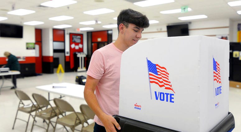 James Fitzgerald, of Boonsboro, Md., a poll worker for the last four months, sets up a voting booth at Northern Middle School in Hagerstown, Md.,