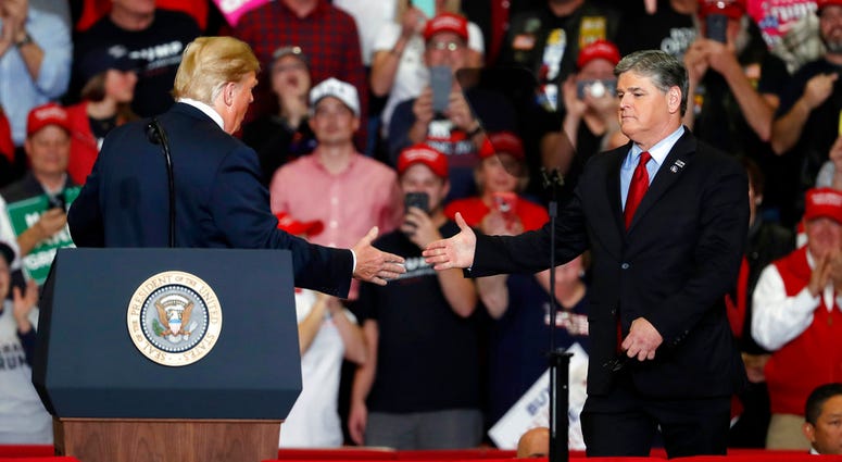 President Donald Trump shakes hands with Fox News Channel's Sean Hannity, right, during a campaign rally Monday, Nov. 5, 2018, in Cape Girardeau, Mo