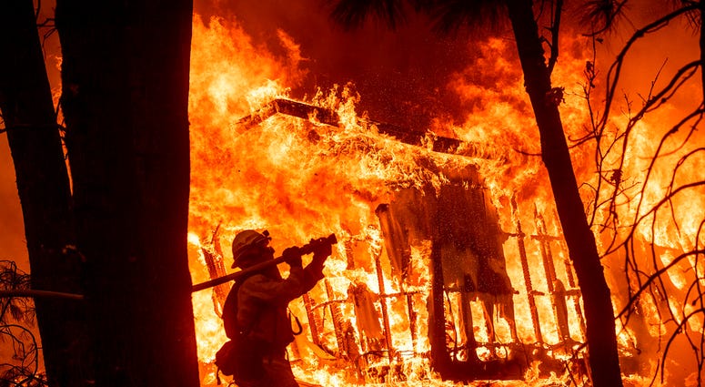 Firefighters work to keep flames from spreading through the Shadowbrook apartment complex as a wildfire burns through Paradise, Calif., on Friday, Nov. 9, 2018.