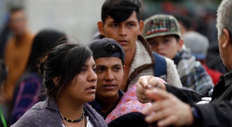 Migrants listen to directions near San Diego