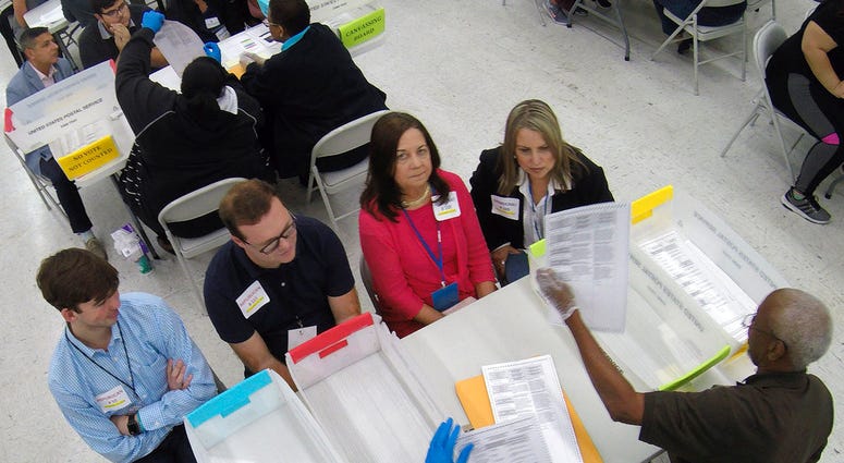 Election workers show ballots to observers