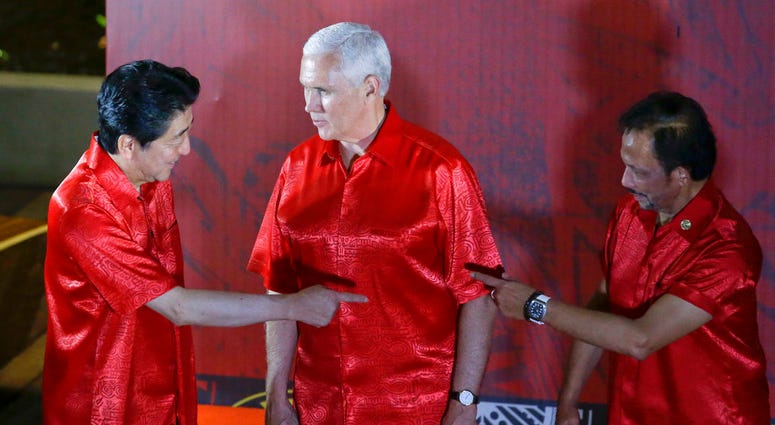 U.S. Vice President Mike Pence, center, watches Japanese Prime Minister Shinzo Abe, left, and Brunei Sultan Hassanal Bolkiah gesture before the start of the gala dinner family photo at the APEC summit in Port Moresby, Papua New Guinea, Saturday, Nov. 17,