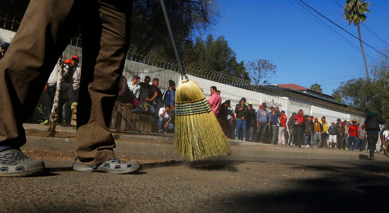 Migrants in background as street is swept