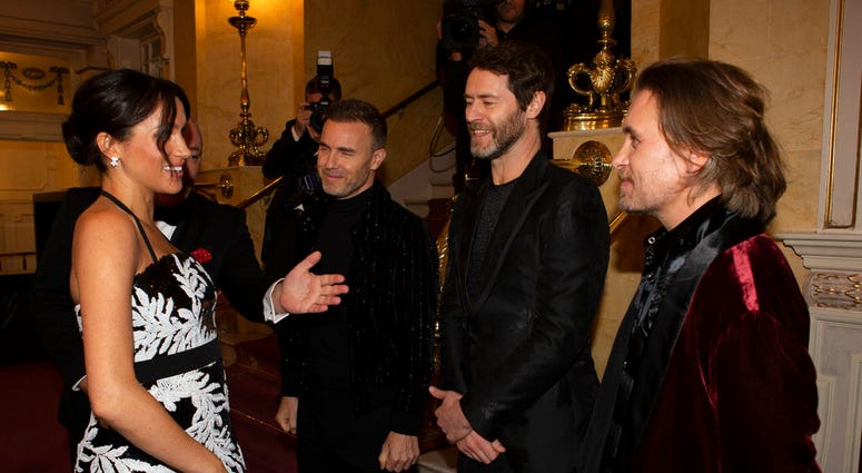 Meghan, the Duchess of Sussex talks to from left Gary Barlow, Howard Donald and Mark Owen of the group "Take That" as she arrives with Britain's Prince Harry